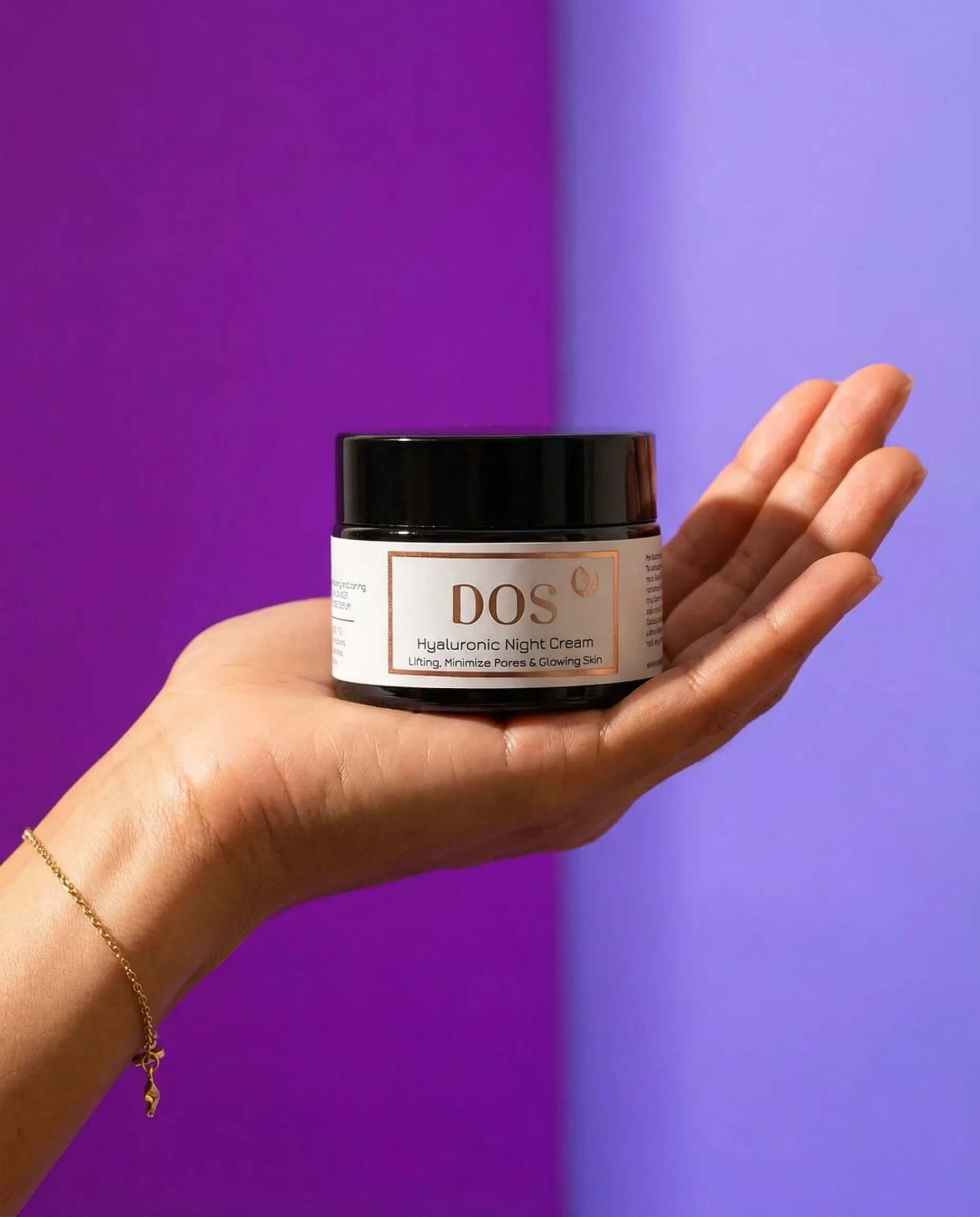 Hyaluronic night cream jar held in hand against a purple background for deep hydration and skin renewal. DOS Cosmetics