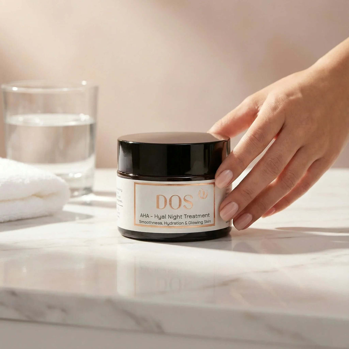 AHA night cream on a marble countertop, hand reaching for the jar, showcasing its hydrating and smoothing properties. DOS Cosmetics