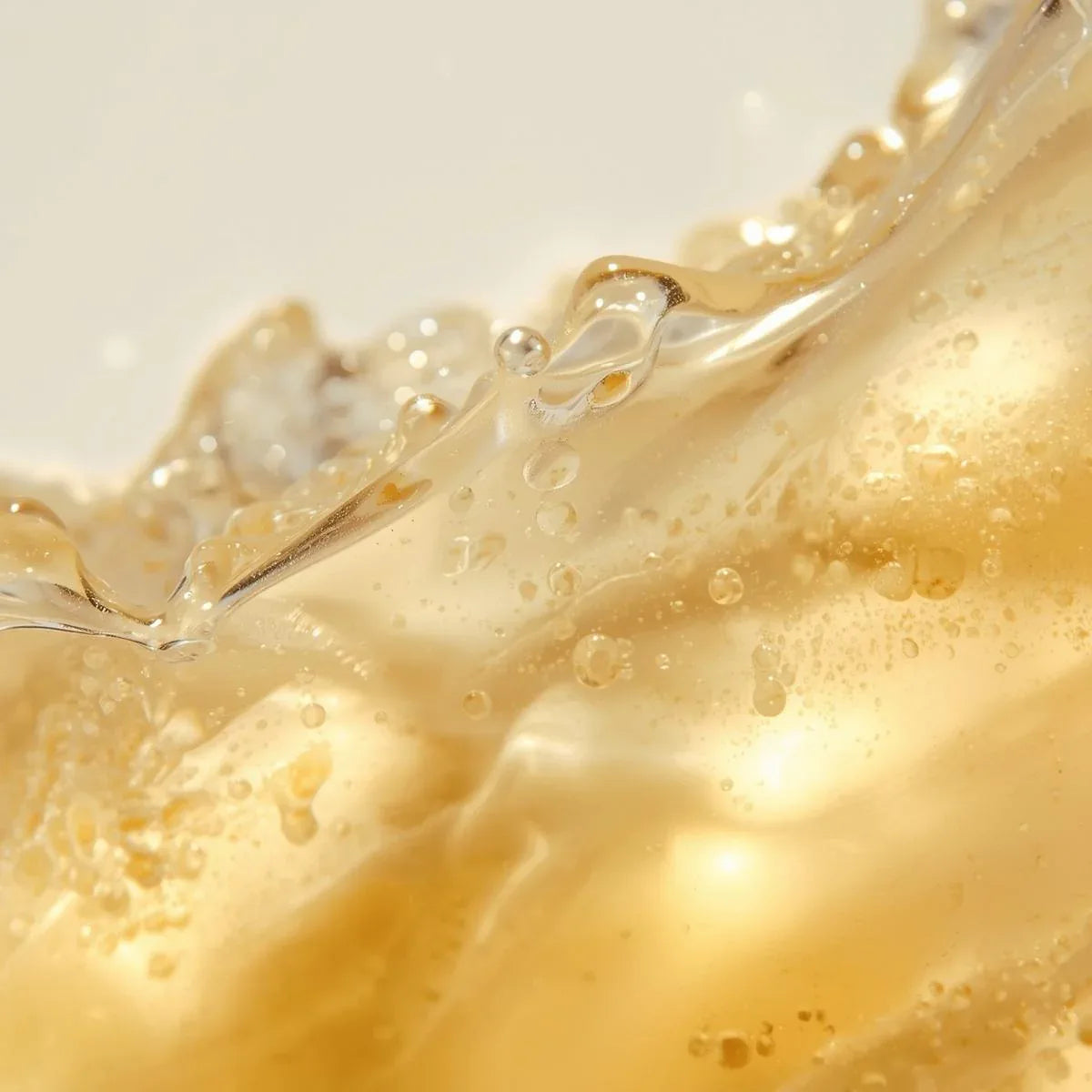 Close-up of golden liquid serum with bubbles on a light background Ascorbin DOS Cosmetics