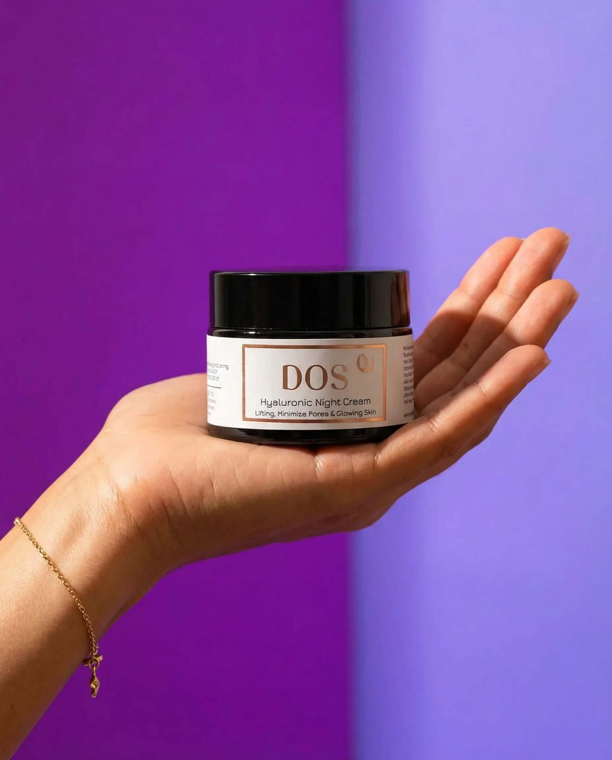 Hyaluronic night cream jar held in hand against a purple background for deep hydration and skin renewal.  DOS Cosmetics