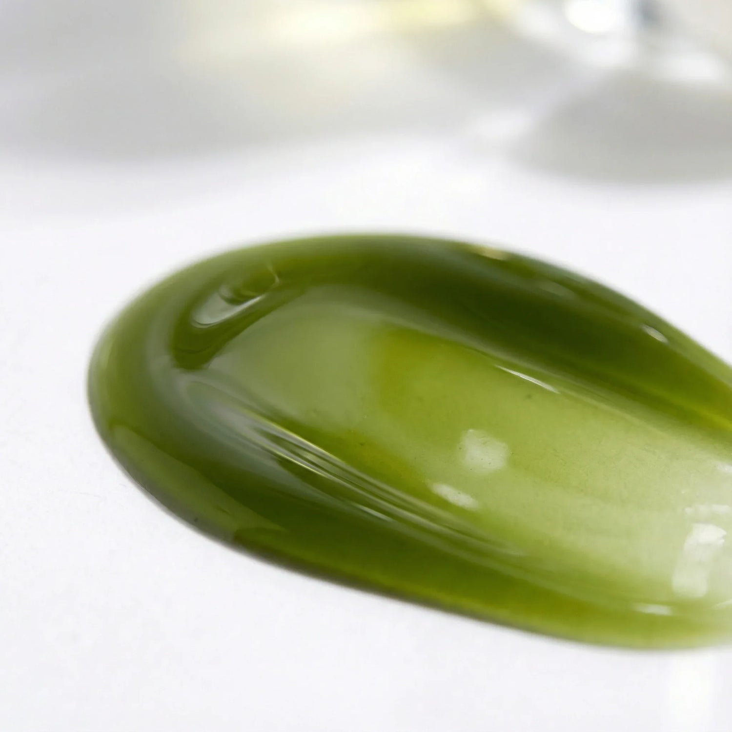 Close-up of green avocado oil droplet on a white background - DOS Cosmetics